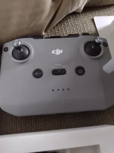 A controller with joysticks and buttons, the letters DJI are visible on the exterior of the controller