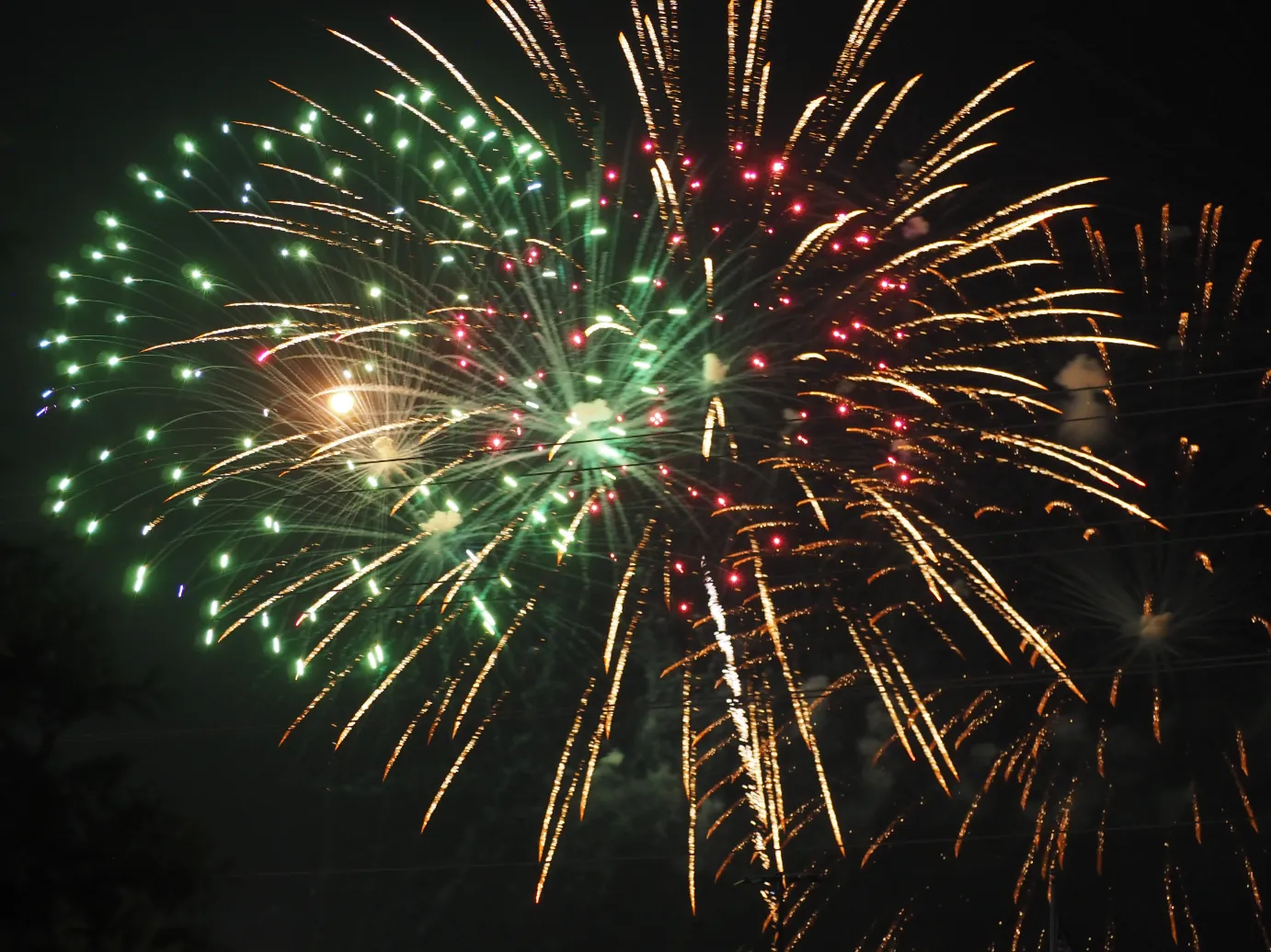 green, yellow, and red fireworks against a black sky