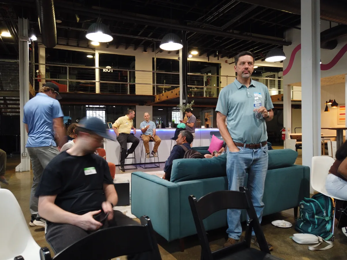 People gathering and networking in a modern, industrial-style office space with a lounge and mezzanine