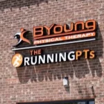 Sign on a brick wall reading BYoung Physical Therapy and The Running PTs