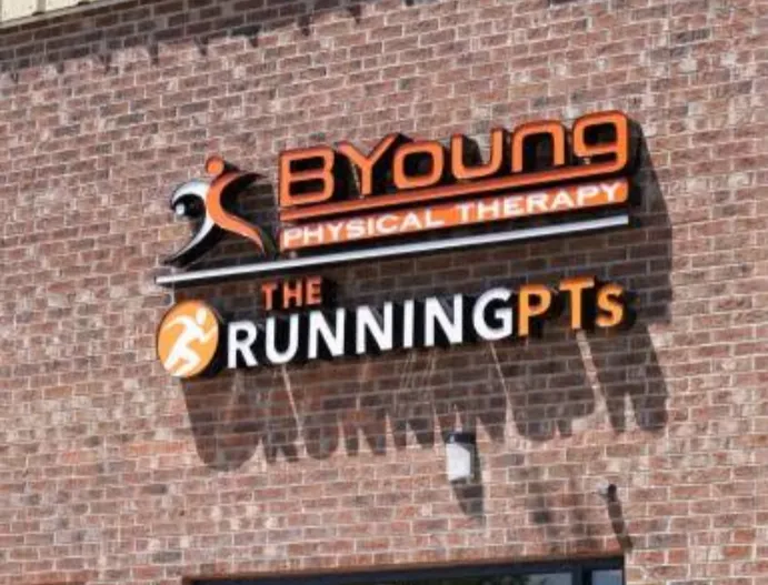 Sign on a brick wall reading BYoung Physical Therapy and The Running PTs